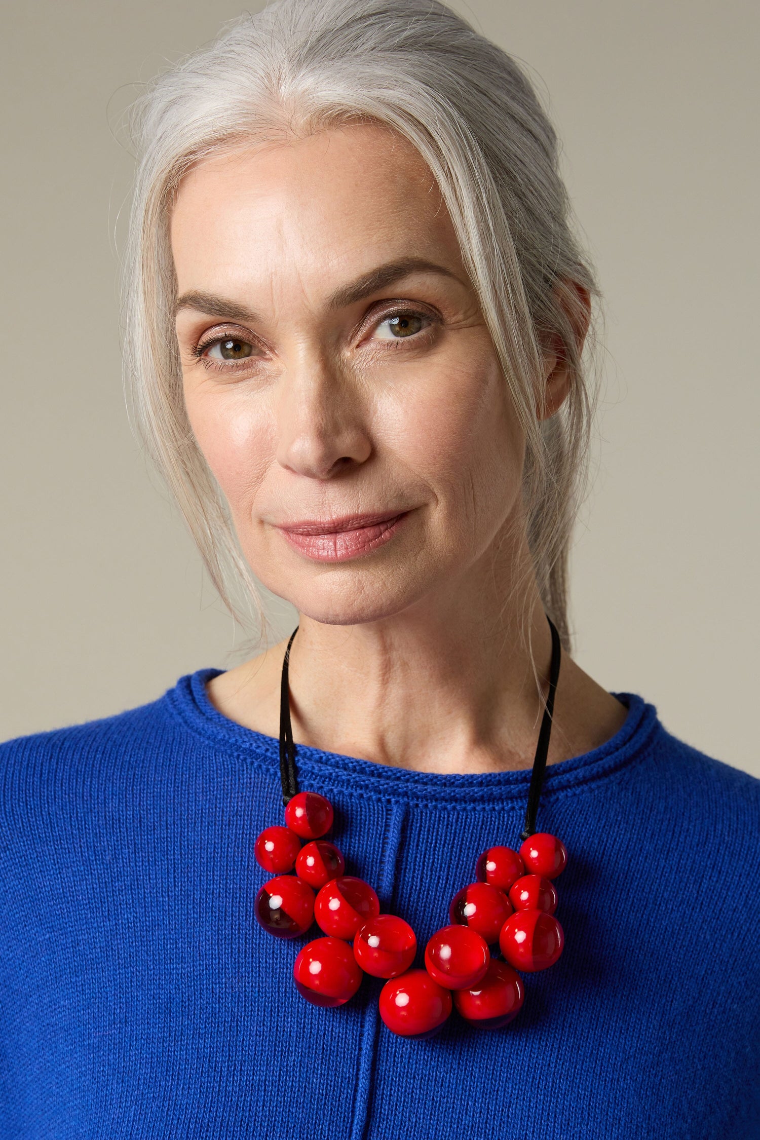 A woman wearing a Spheres Necklace with red beads by Zsiska.