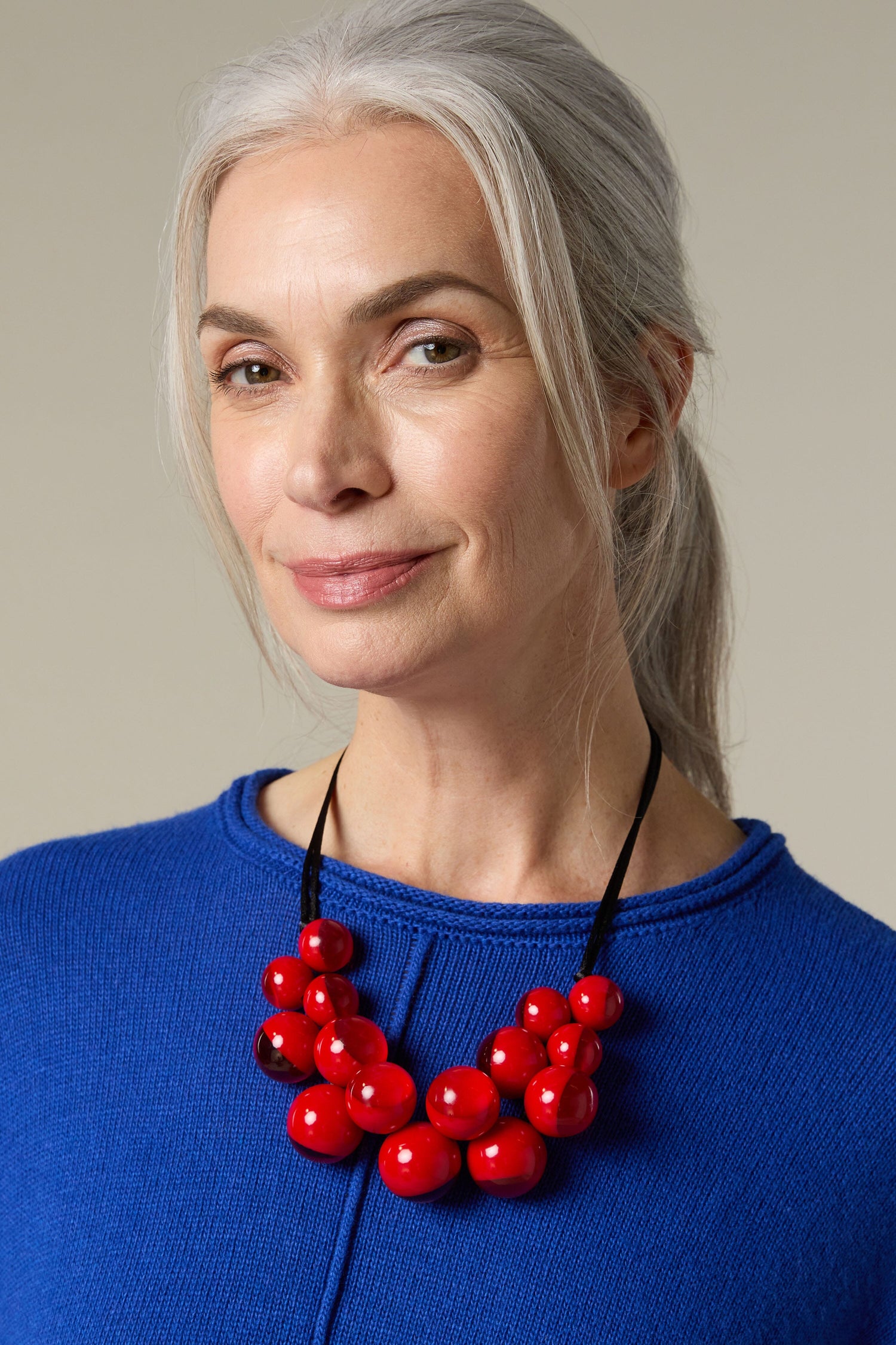 A woman wearing a Spheres Necklace with red beads by Zsiska.