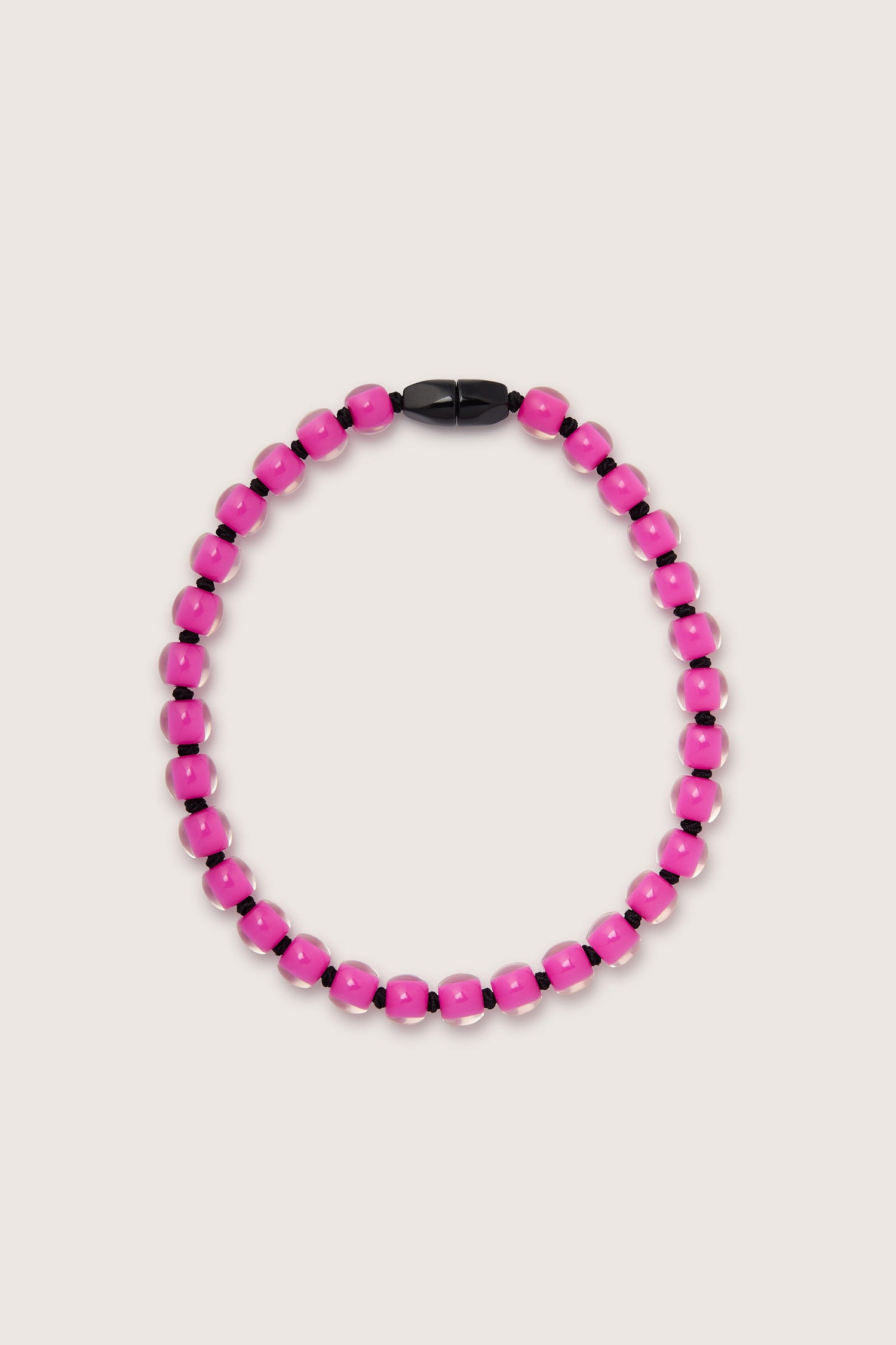 A Colourful Beads Necklace made of bright pink resin beads and a black magnetic closure on a light background.