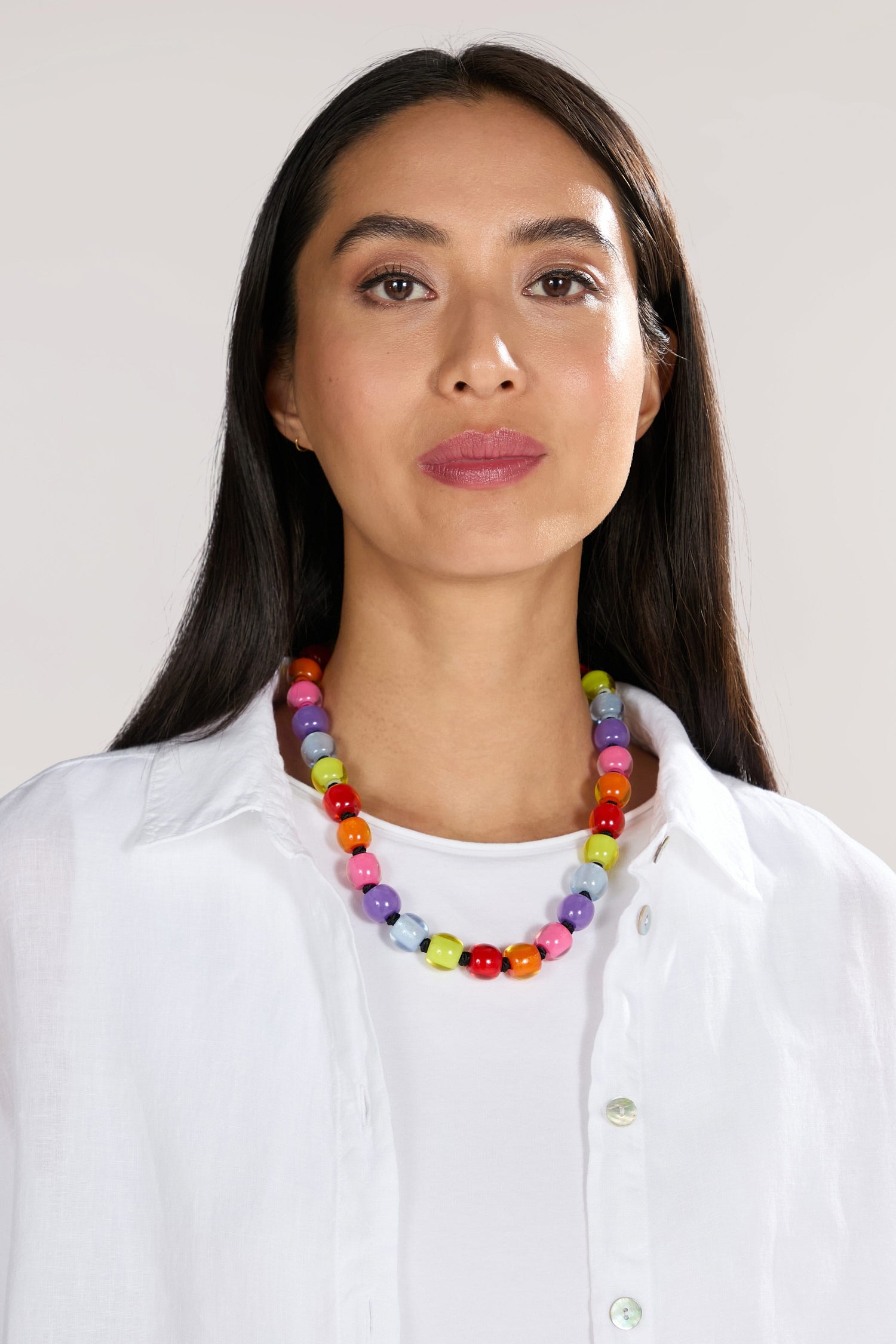 A woman with long dark hair wearing a white shirt and a Colourful Beads Necklace featuring vibrant resin beads.