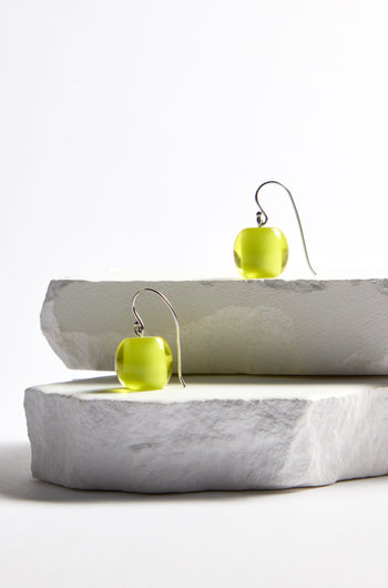 Part of the Bellisima Collection, the Colourful Bead Earrings feature green spherical beads with curved hooks, elegantly displayed on stacked stone slabs against a white background.