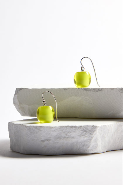 Part of the Bellisima Collection, the Colourful Bead Earrings feature green spherical beads with curved hooks, elegantly displayed on stacked stone slabs against a white background.