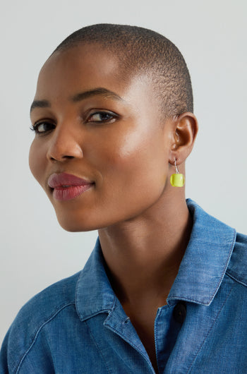 Person wearing a blue denim shirt and Colourful Bead Earrings, with a neutral expression against a light background.