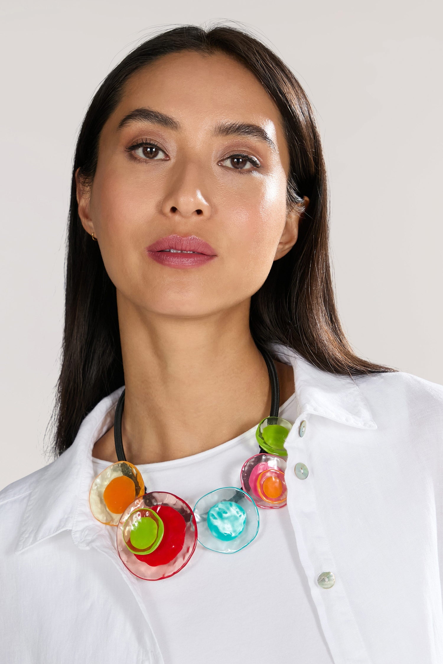 A person with long dark hair wears a white shirt and a vibrant Short Resin Flower Necklace, showcasing artistic expression in its colorful, multi-disc design.