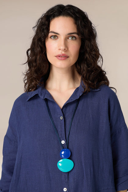 A woman wearing a blue shirt and Resin Sphere Pendant necklace with organic shapes.