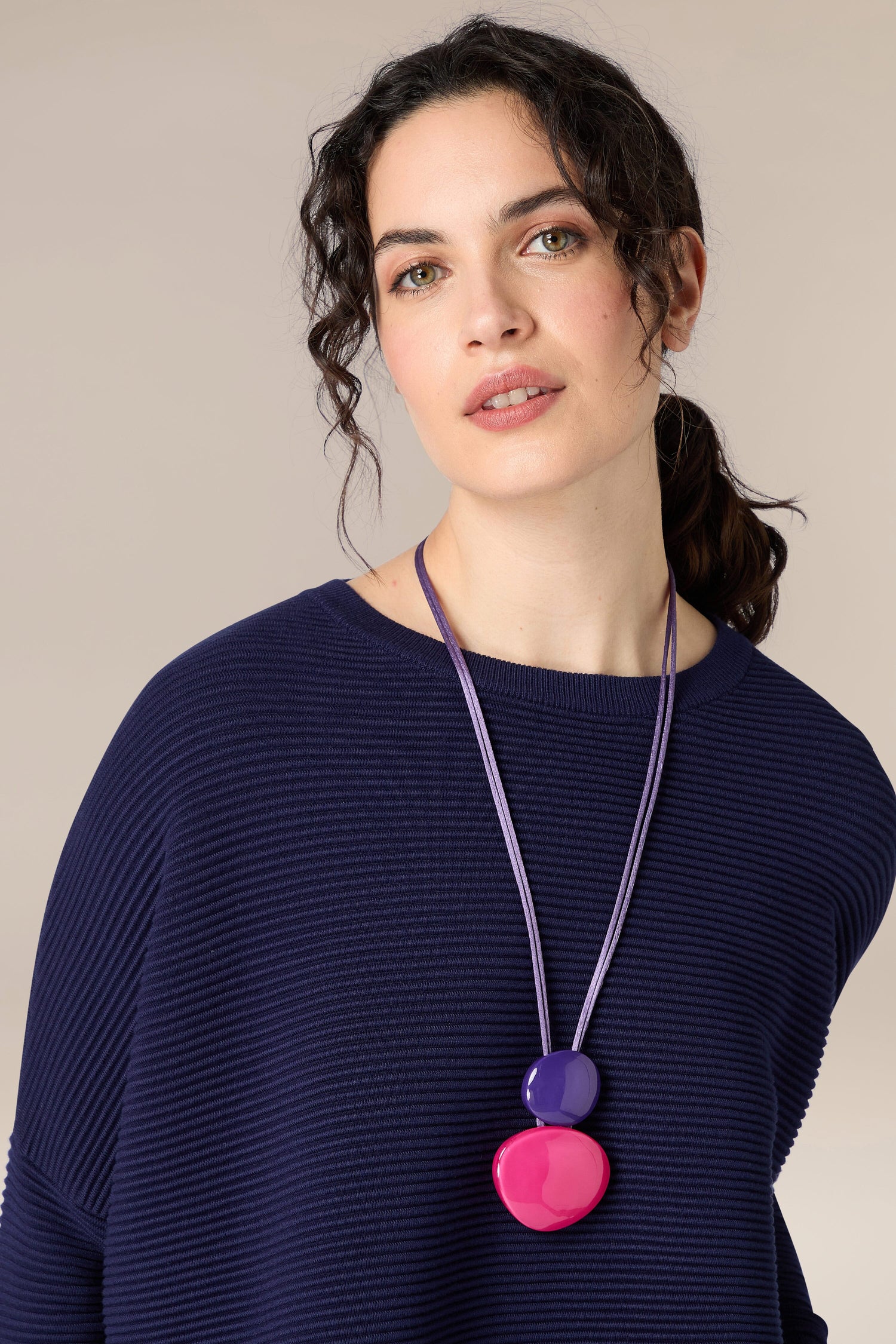 A woman wearing a navy sweater with a Resin Sphere Pendant necklace.