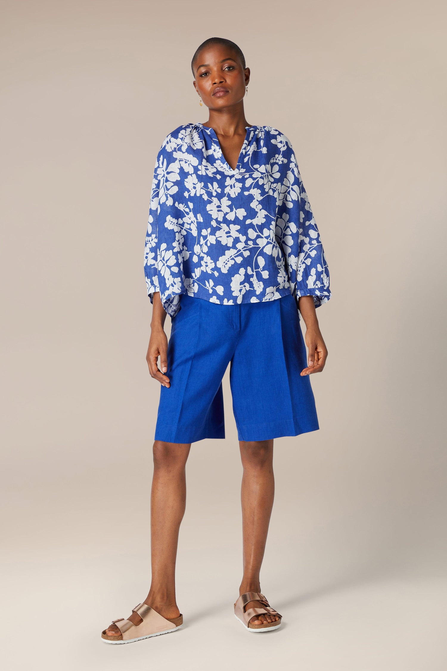 A woman in Bradley Linen Shorts and white outfit.