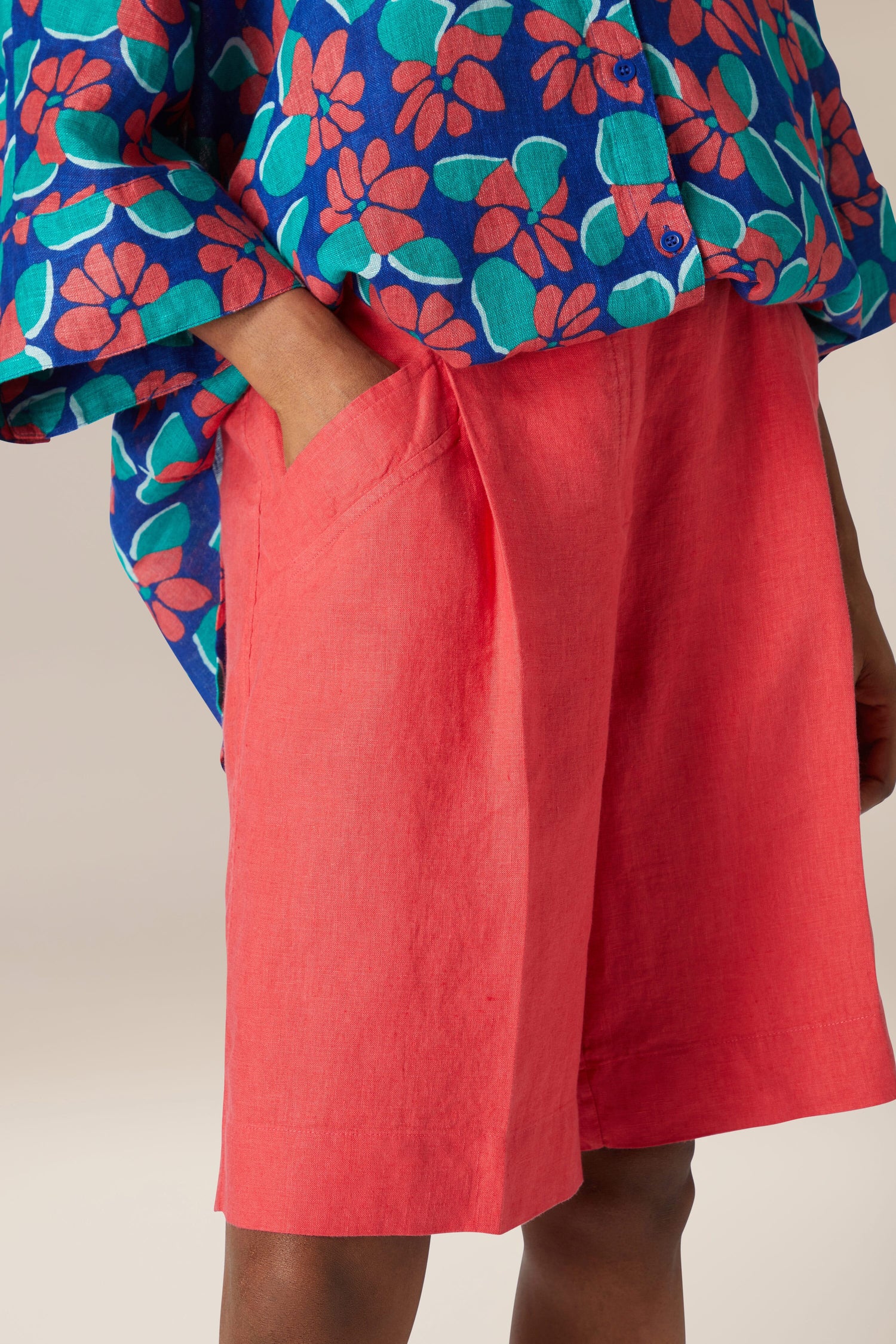 A person wearing our Bradley Linen Shorts with a floral shirt and a blue shirt.