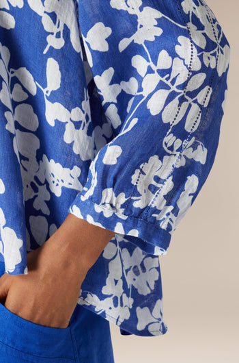 Close-up of a person wearing a Billie Linen top with a blue floral pattern, focusing on the sleeve detail.