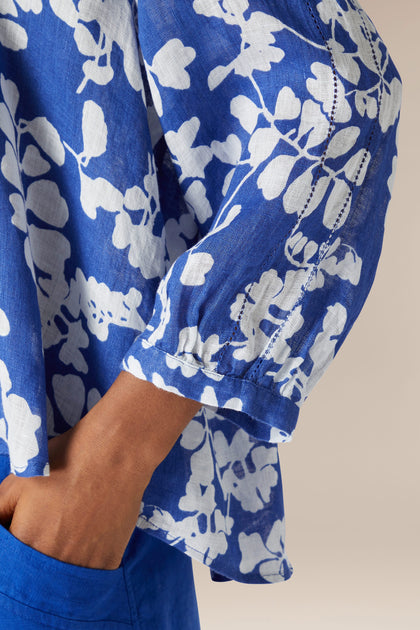 Close-up of a person wearing a Billie Linen top with a blue floral pattern, focusing on the sleeve detail.