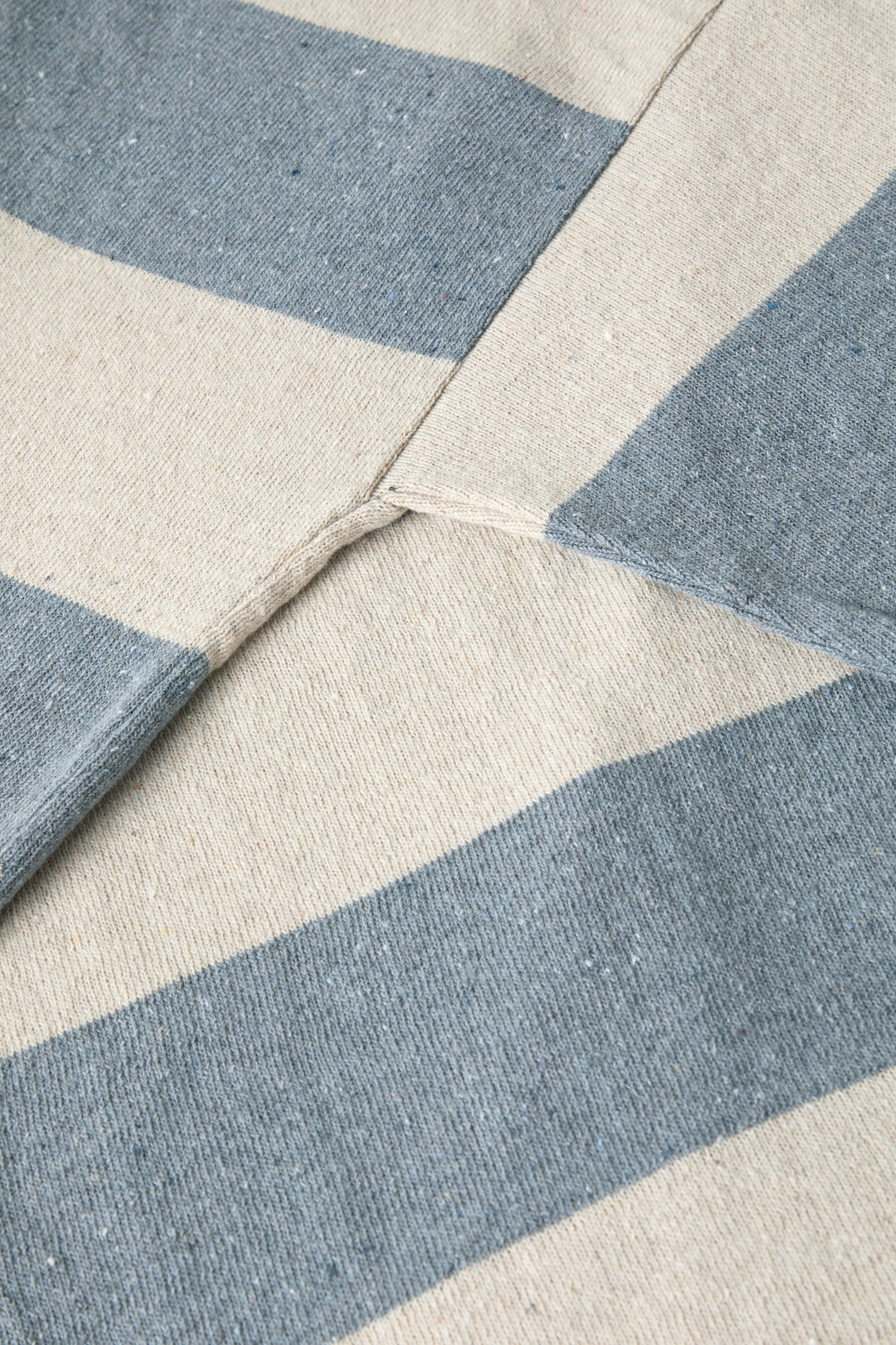 Close-up view of a Vera Stripe Top, beige and blue striped fabric with a visible seam and stitching details.