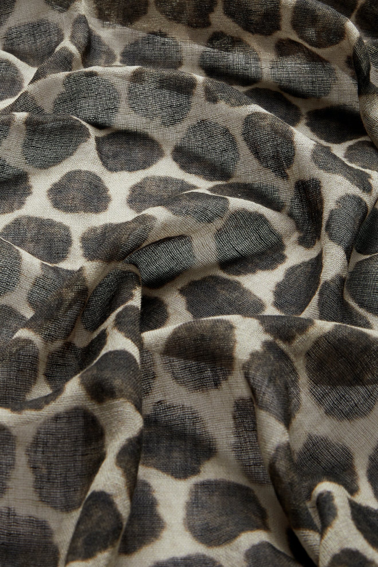 Close-up of the Circle Spot Scarf—a sheer, lightweight accessory featuring a black and gray circular spot pattern, slightly wrinkled and elegantly draped.