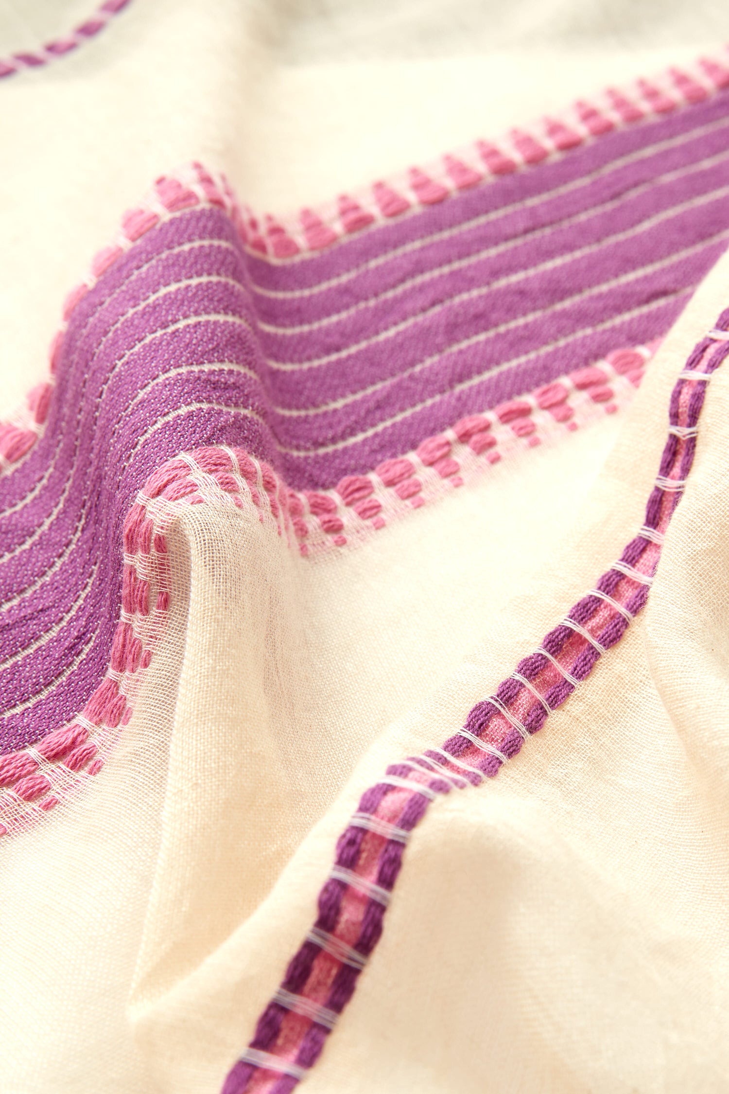 Close-up of a Embroidered Stripe Scarf with purple and pink embroidered stripes and decorative fringe.