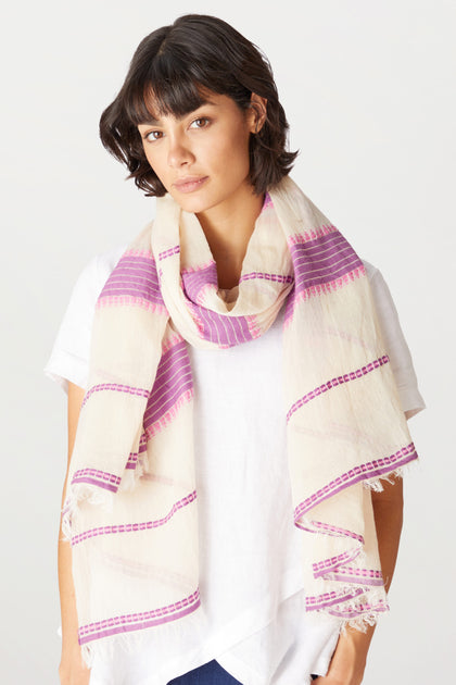 Woman in a white blouse wearing an Embroidered Stripe Scarf, looking at the camera, with a slight smile on her face.