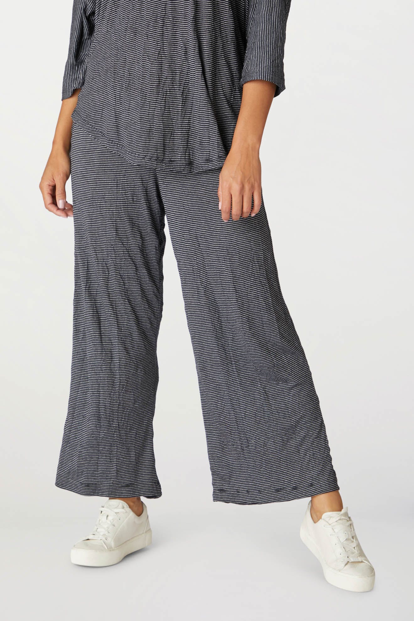 A person wearing navy blue textured Stripe Pant with an elasticated waist and white sneakers, partially visible with a focus on the lower body.