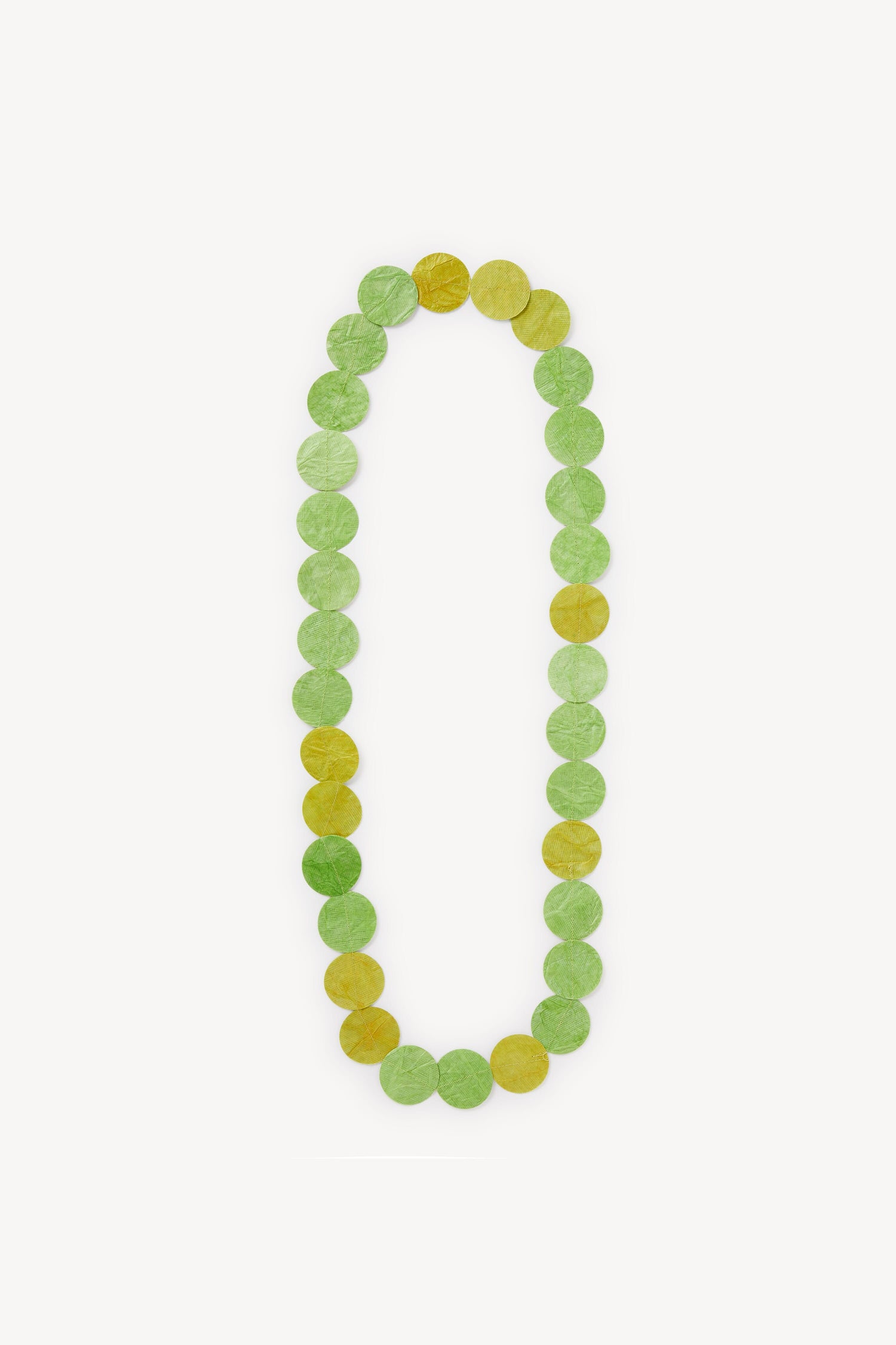 The Dotty Necklace forms a vertical number zero "0" with alternating green and yellow translucent candy discs, resembling delicate leaves, on a white background.