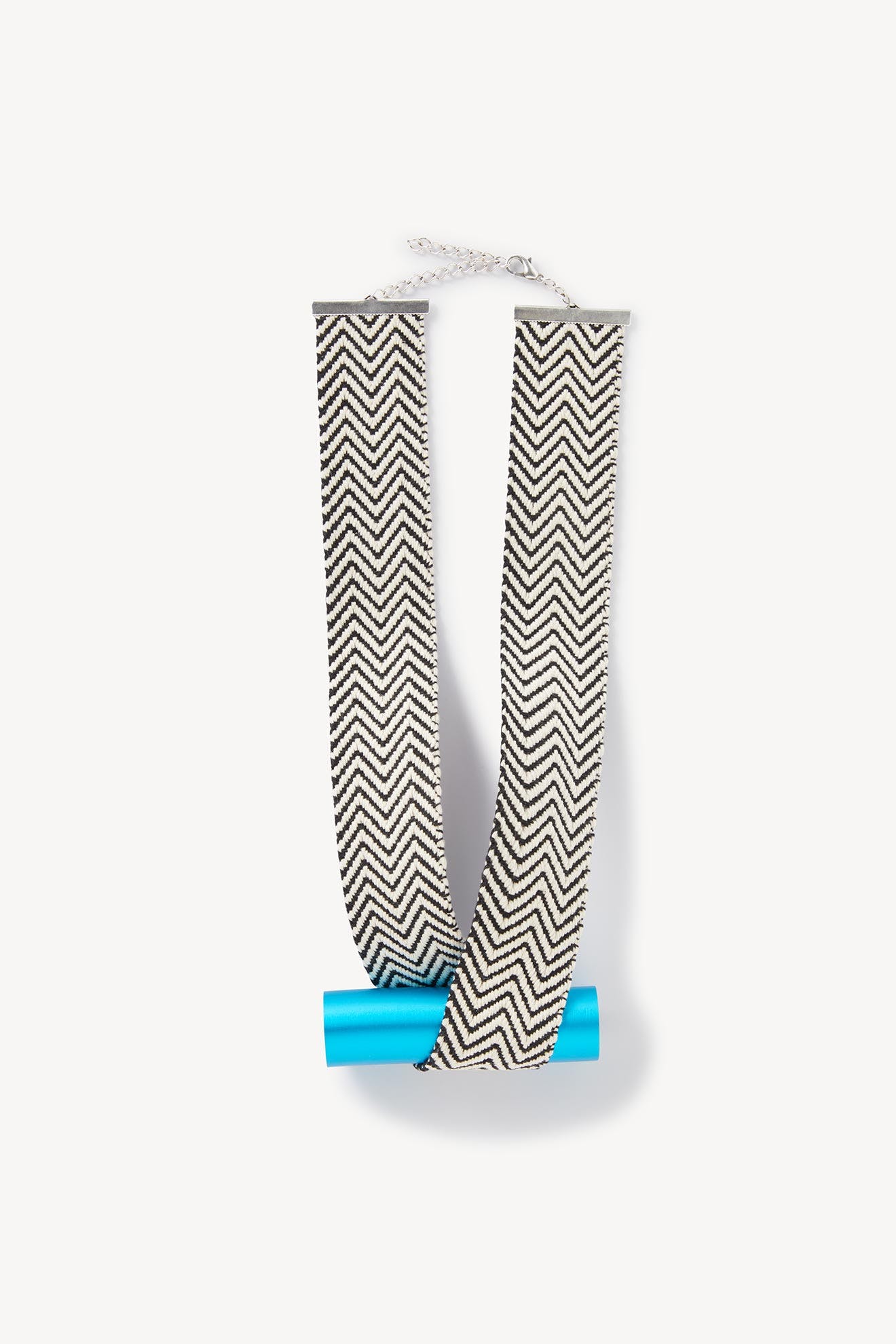 Sentence with Product Name: Black and white chevron-patterned ribbon draped over a rolled blue document, isolated against a white background, resembling the Balance Necklace.