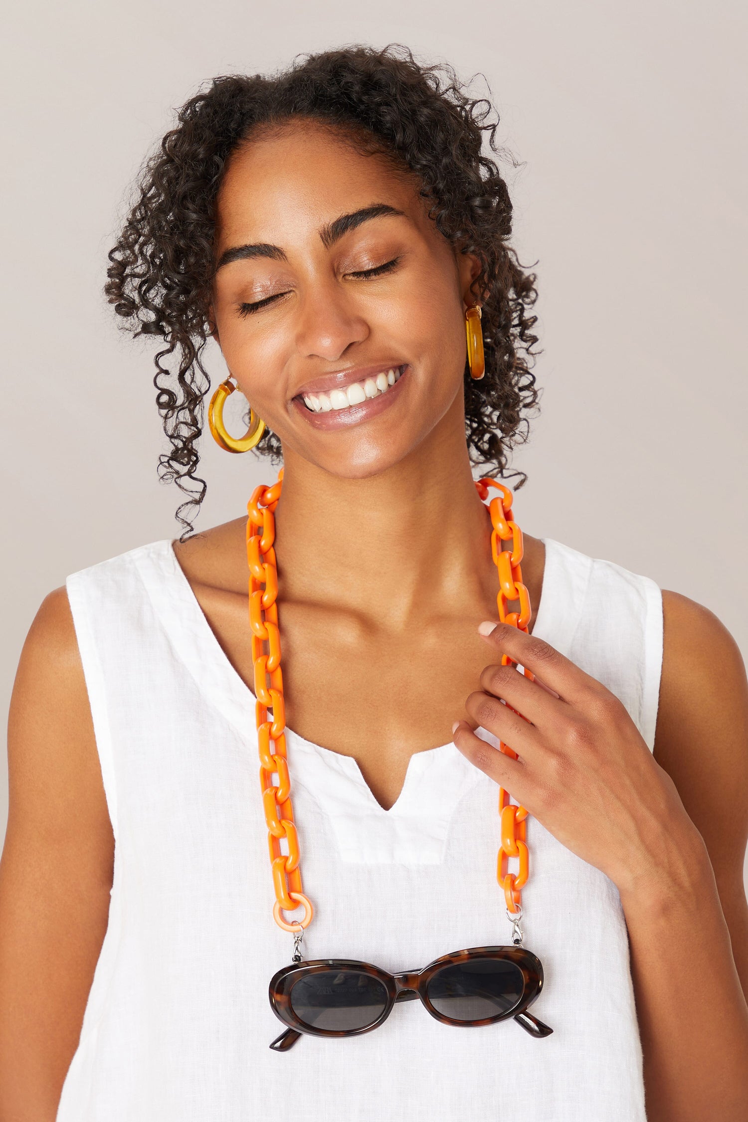 A woman wearing sunglasses and an Anima Glasses Chain necklace.