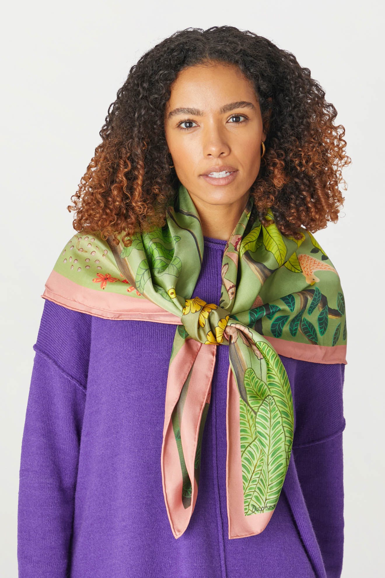 An artist wearing a purple sweater with a green and pink Are You Coming With Me Silk Scarf.