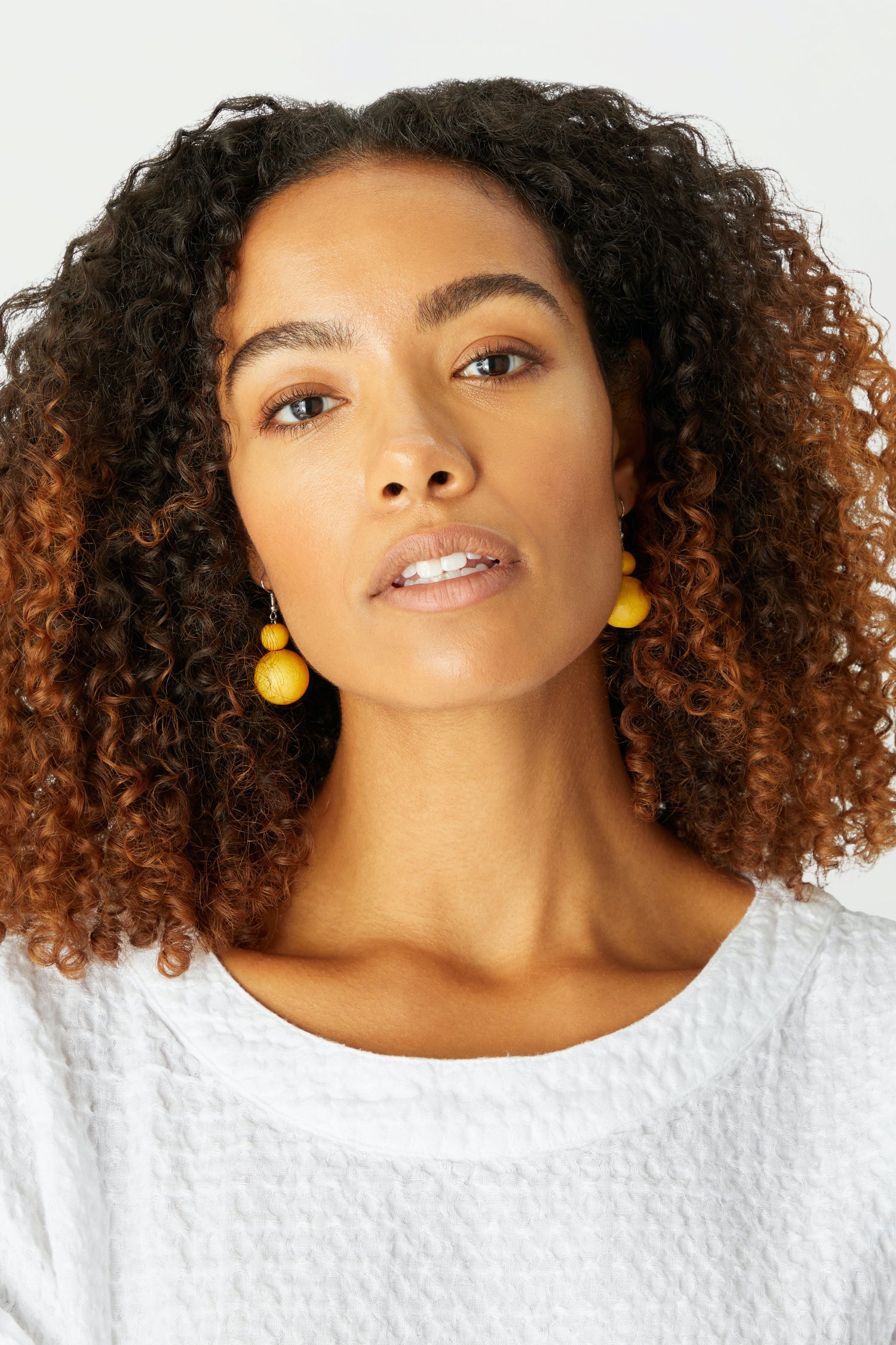 A woman with curly hair wearing Double Sphere Earrings.