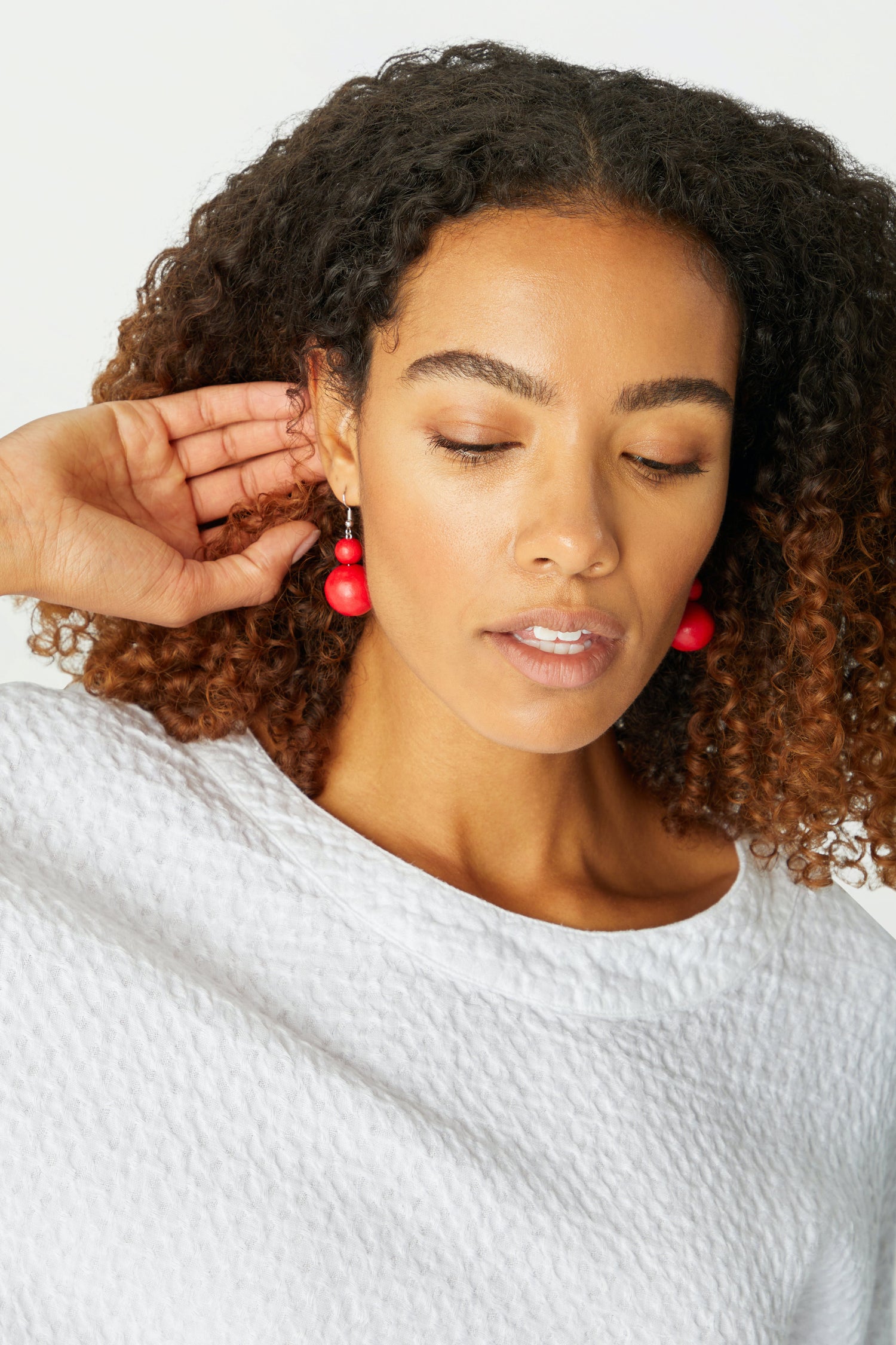 A woman wearing a white sweater and Double Sphere Earrings from a jewellery brand.