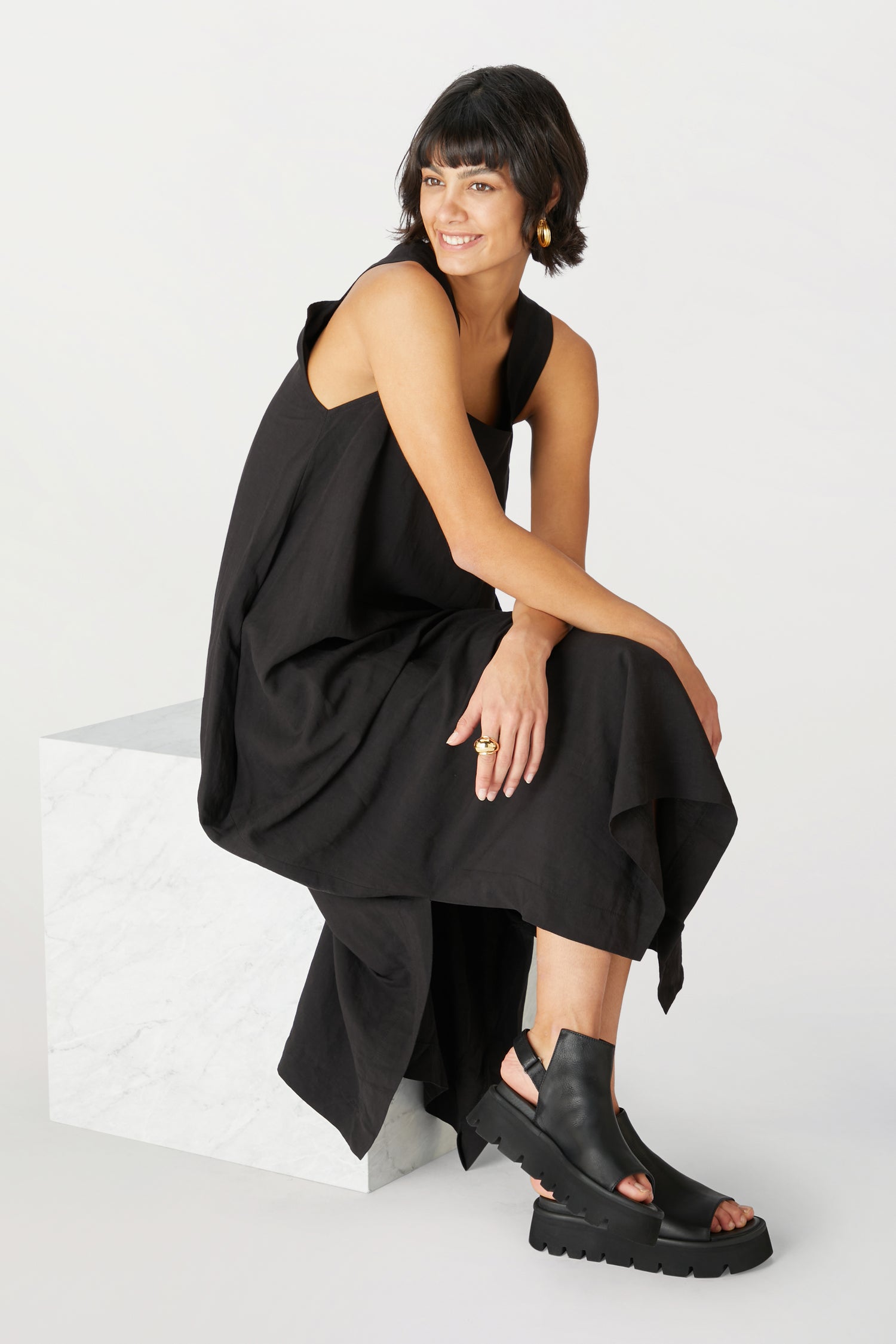 A woman wearing Lofina shoes, showcasing a minimalist style with a black dress and Buckle Back Sandals.