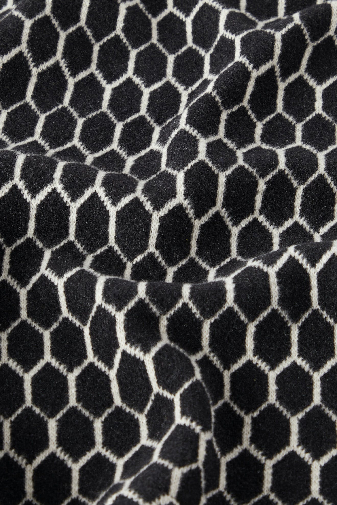 The Honeycomb Top, featuring a black and white honeycomb pattern with visible folds, highlights the craftsmanship of Italian artisans.