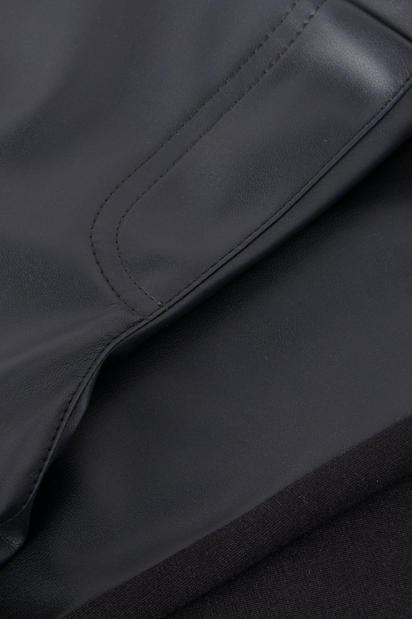 Close-up of a black vegan leather leggings showing detailed stitching on the pocket.