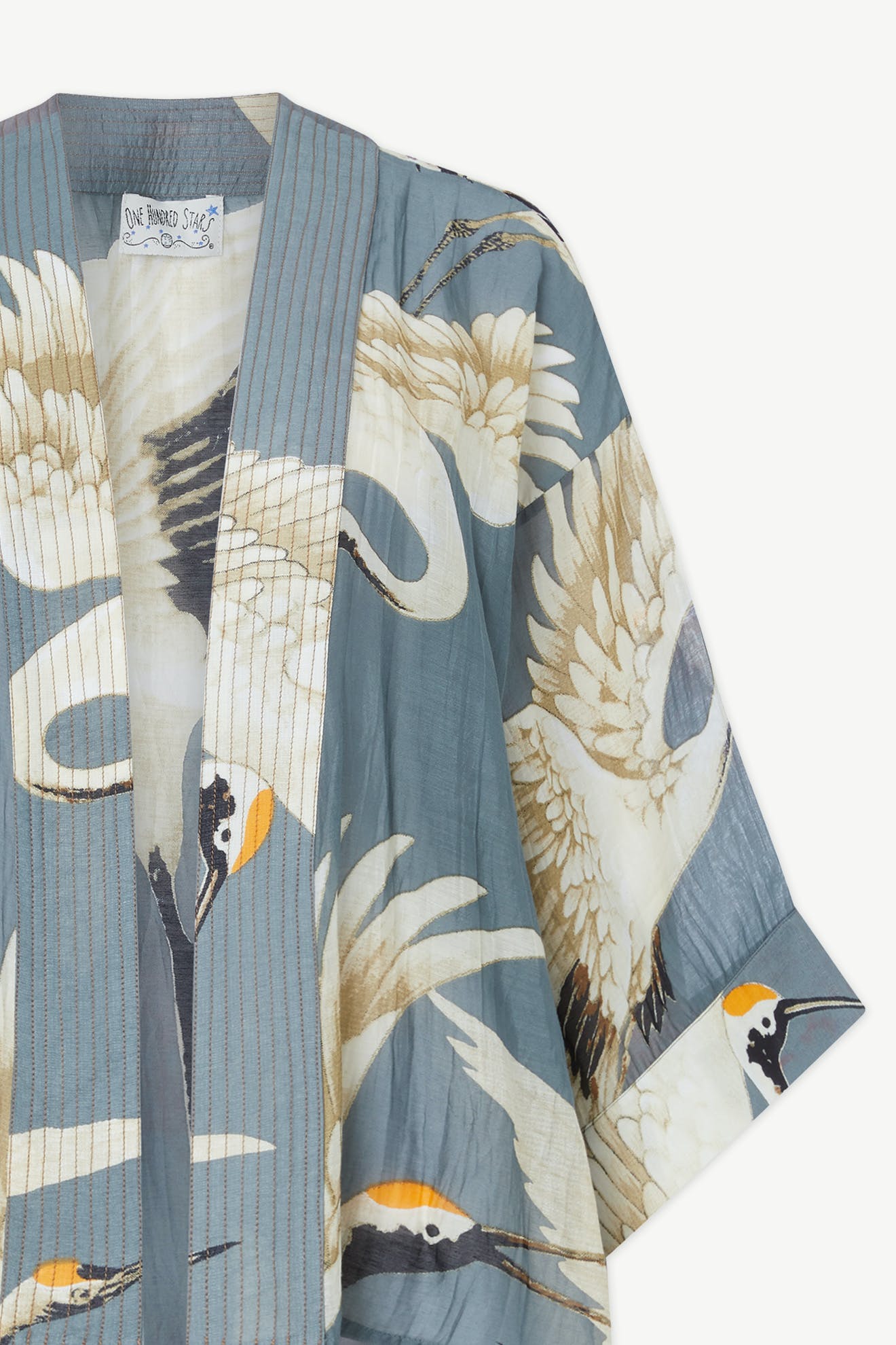 Close-up of the Stork Kimono in lightweight modal viscose, featuring a beautiful crane pattern and a fabric label on the collar, inspired by the Kew Gardens collaboration.