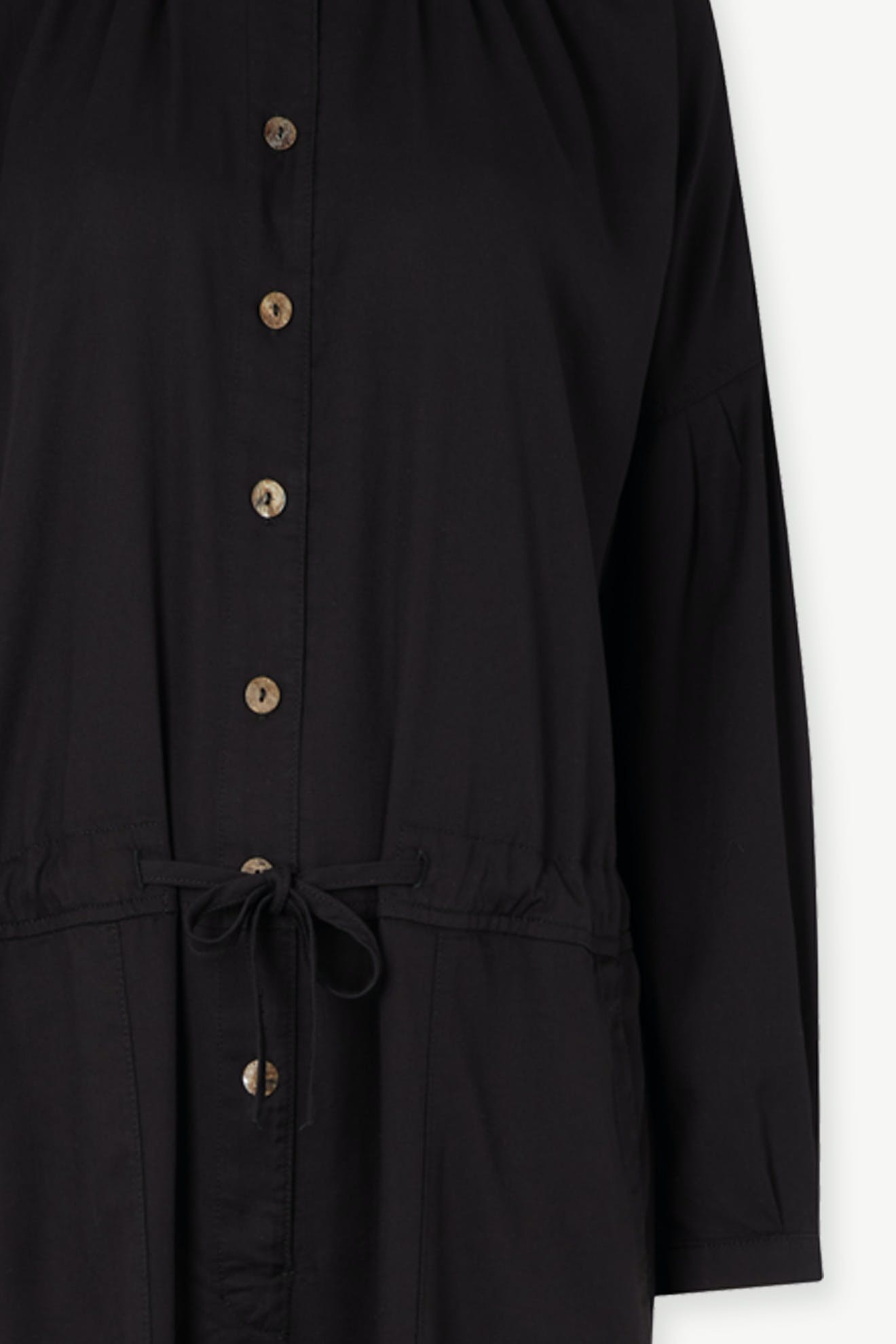 Close-up of a black Drape Tencel Twill Jumpsuit with buttons and a waist tie detail.