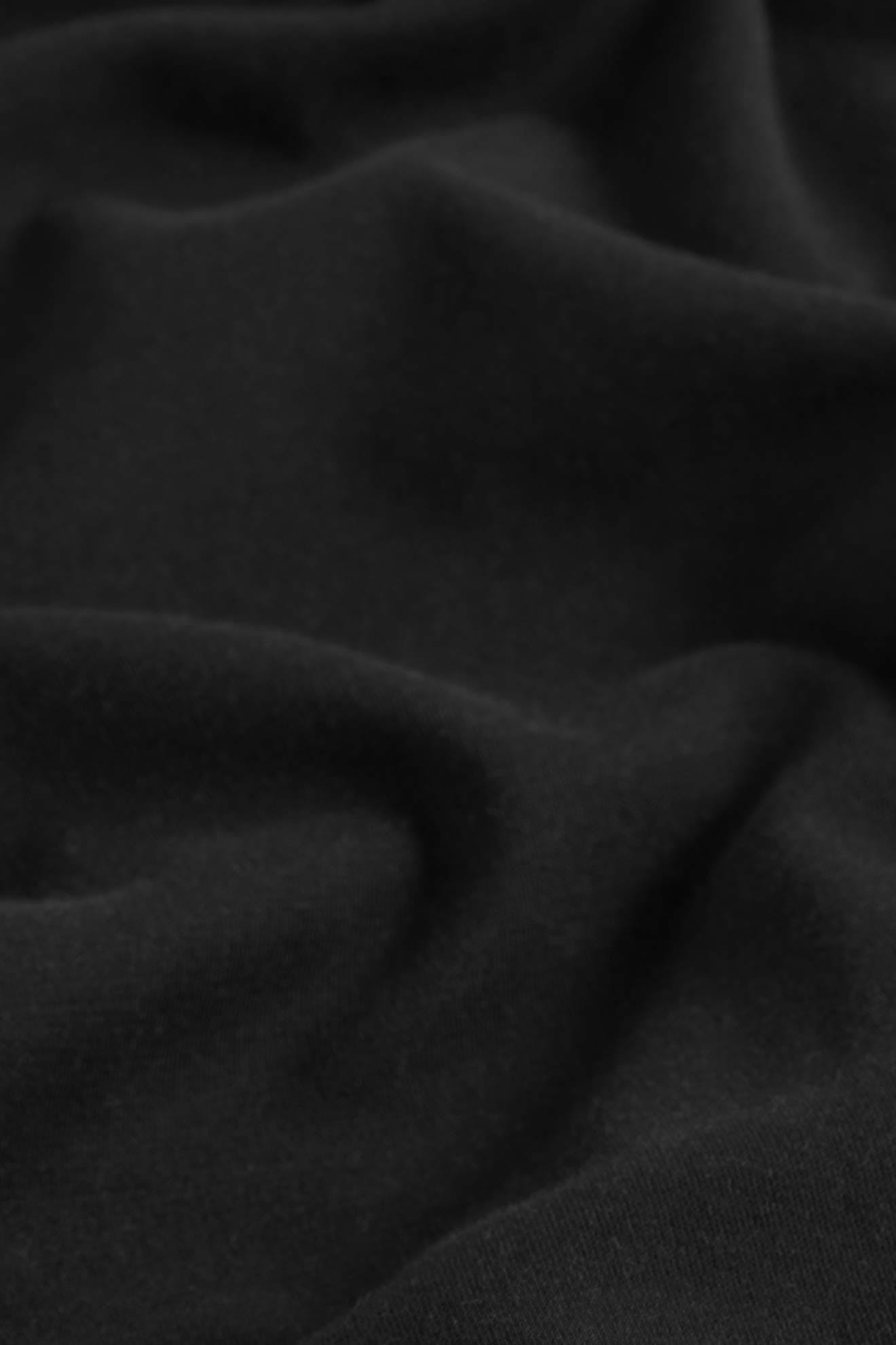 Close-up of black OEKO-TEX cotton fabric with soft folds and smooth texture, perfect for the SS22 Stretch Cotton Trouser featuring an elasticated waist and slim-leg tapered fit.