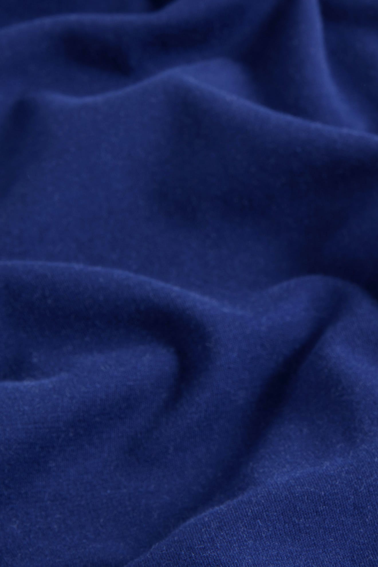 A close-up view of the SS22 Stretch Cotton Trouser in dark blue OEKO-TEX cotton, featuring soft folds and a slightly textured surface.