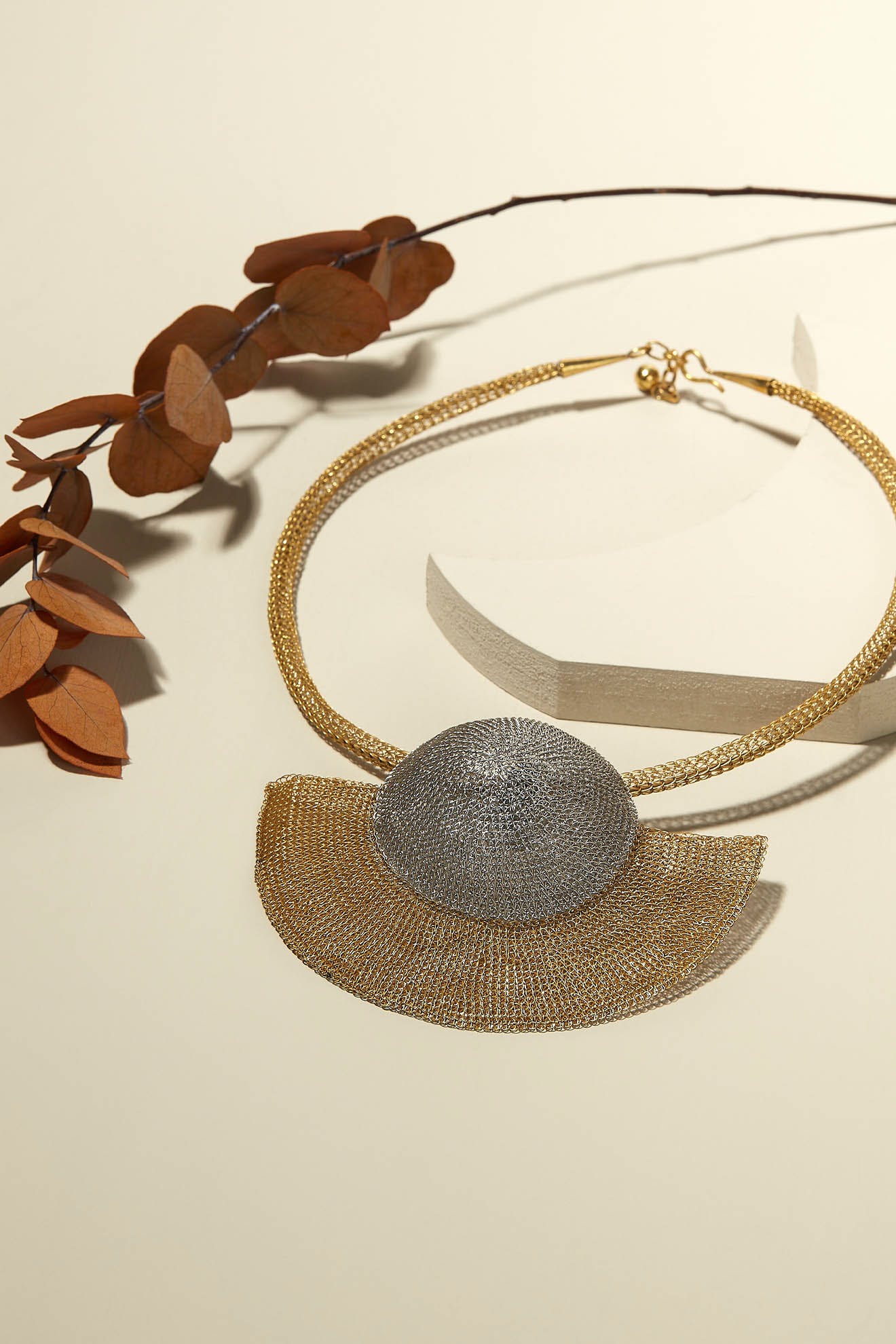 This Soninké Jewellery Crochet Half Moon Necklace showcases a delicate leaf pendant with stunning silver and gold finishes.