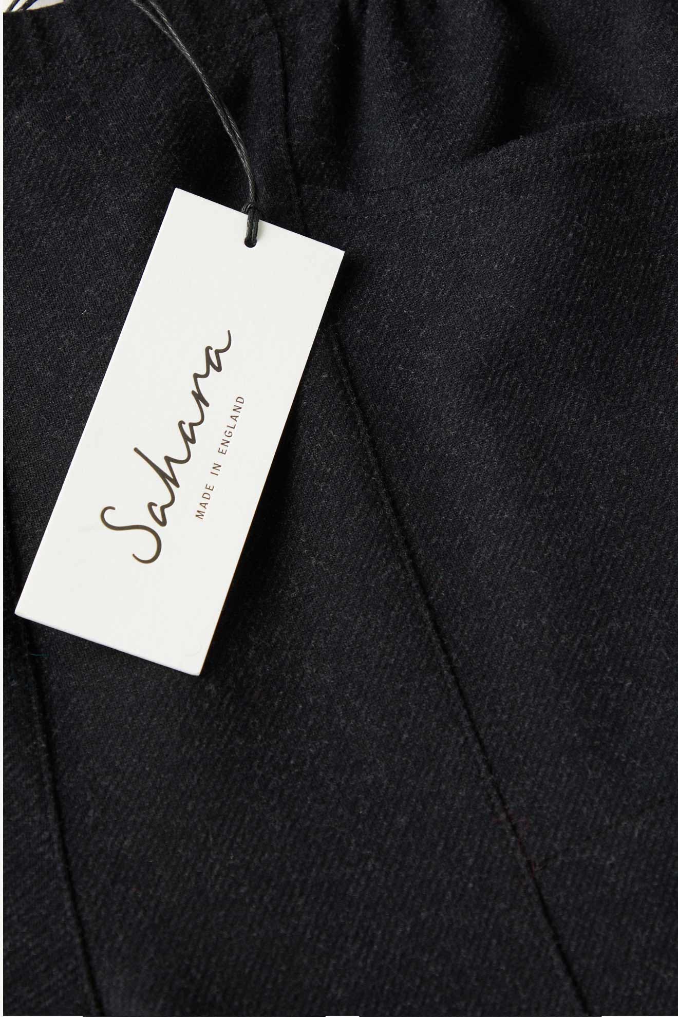 Close-up of black AW21 Marl Jersey Bubble Trouser with a white brand tag reading “Sahara Made in England.”