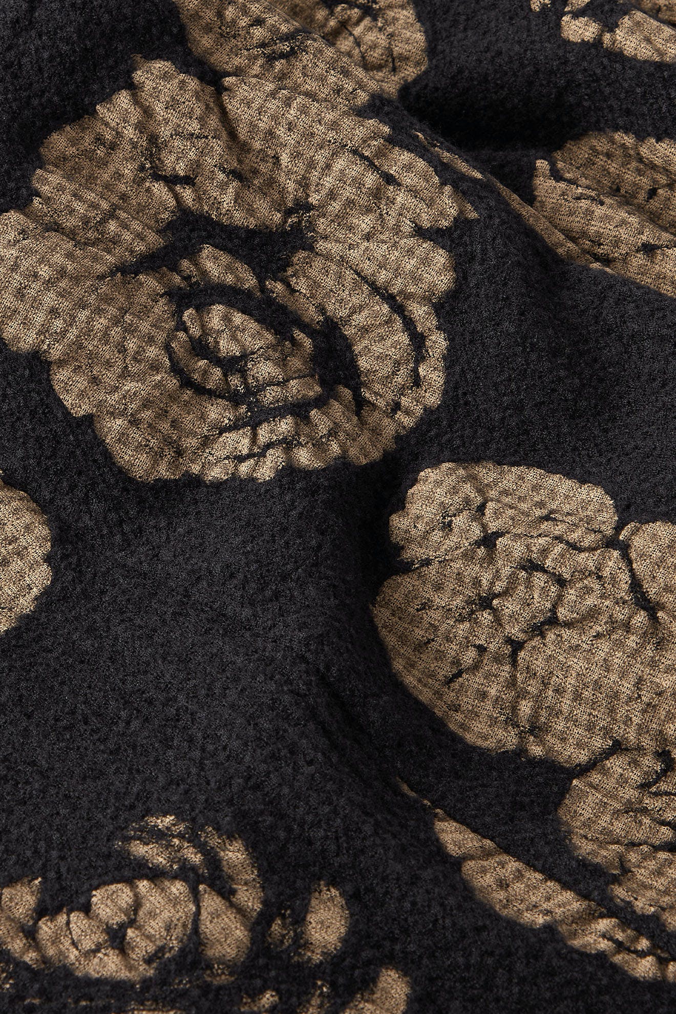 Close-up of a textured fabric featuring a black and gold Rose Print Pant pattern.