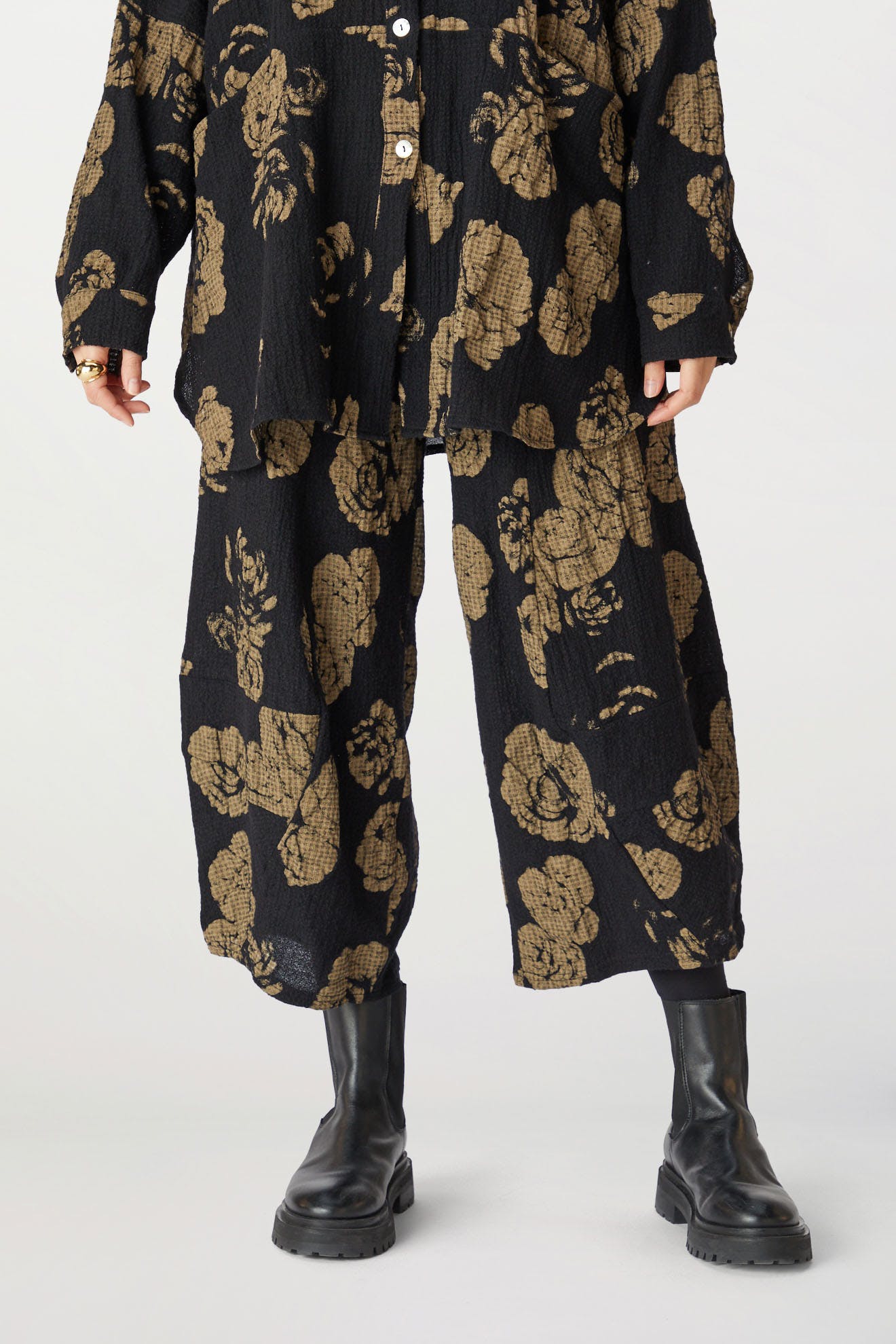 A person wearing a dark rose print jacket and matching Rose Print Pant with an elasticated waist, paired with black boots, standing against a neutral background.
