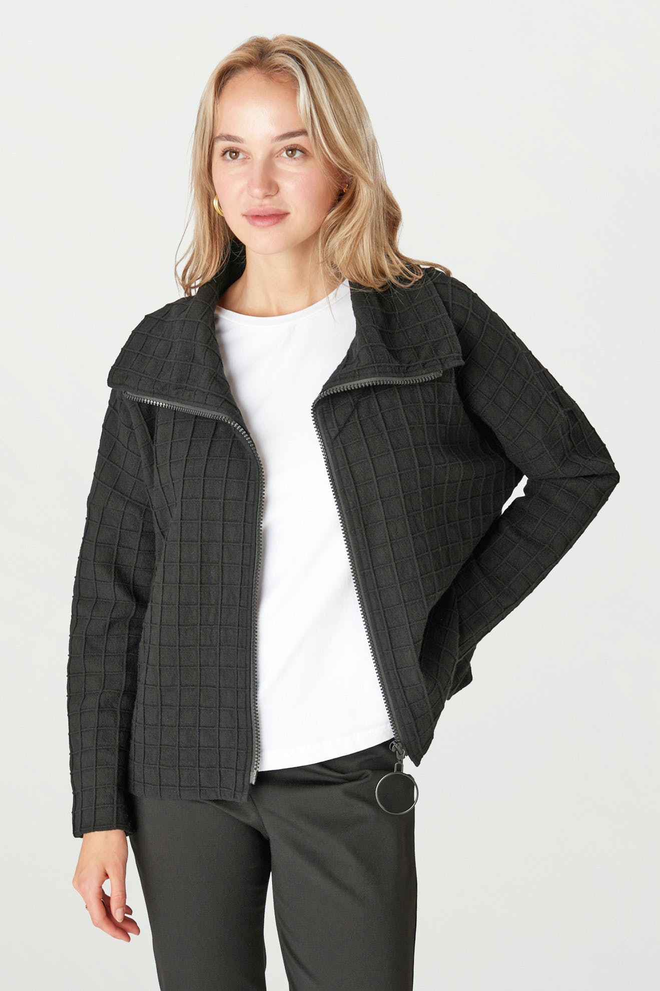 A person wearing the Window Pane Wool Jacket, featuring a black quilted design with an oversized folded collar, over a white shirt, stands against a plain background.