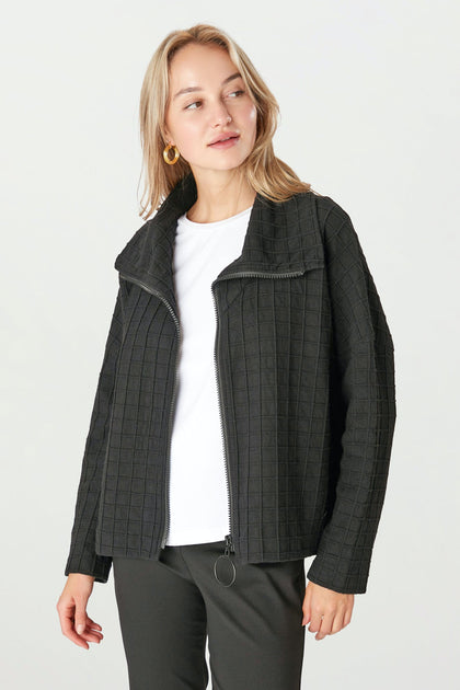 A person wearing the Window Pane Wool Jacket, featuring a black quilted design and an oversized folded collar, over a white shirt stands against a plain background.