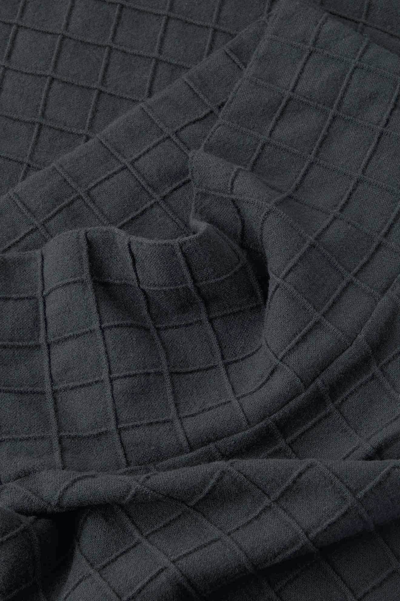The Window Pane Wool Top features a dark gray color with a raised grid pattern, highlighting its folds and textured surface.