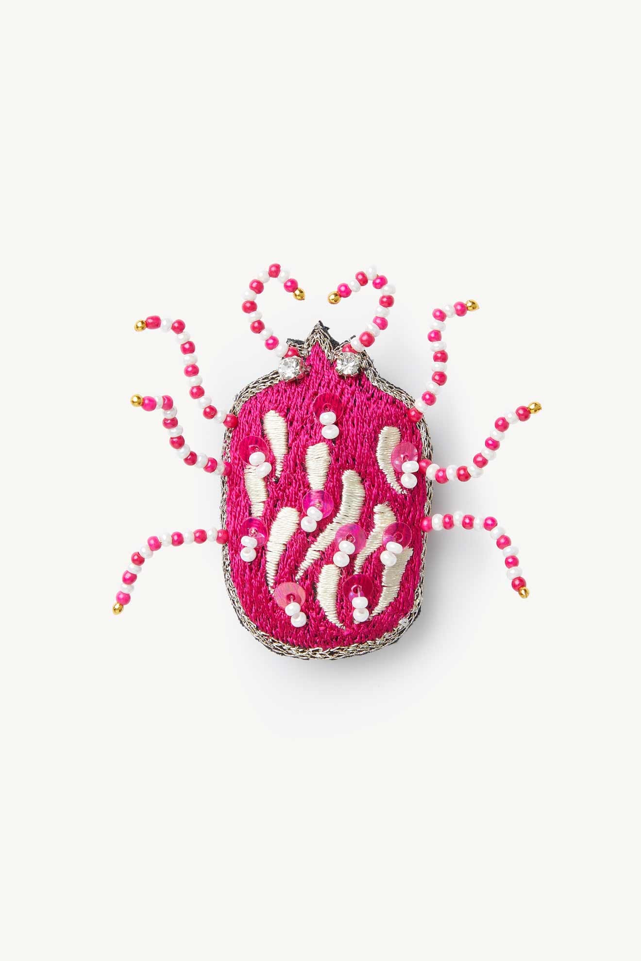 The Pink Detail Beetle Brooch features a bug-shaped design with a pink embroidered body, white and pink seed bead accents, and beaded legs, displayed on a plain white background.